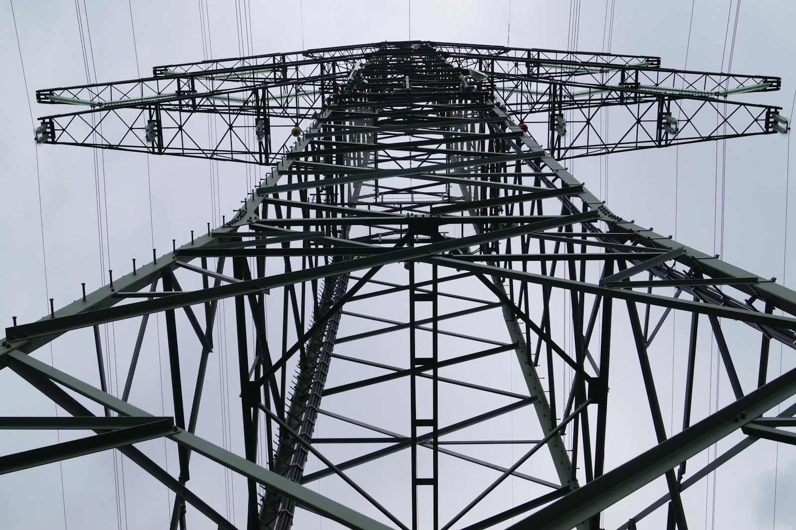 Close-up low angle view of a metal electricity pylon against a cloudy sky.